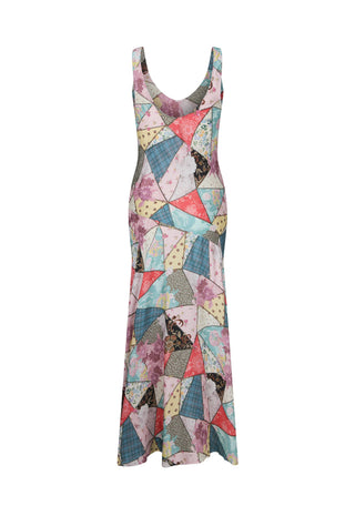  wearing a colorful patchwork print maxi dress with butterfly and floral motifs. The dress features a mix of pastel pink