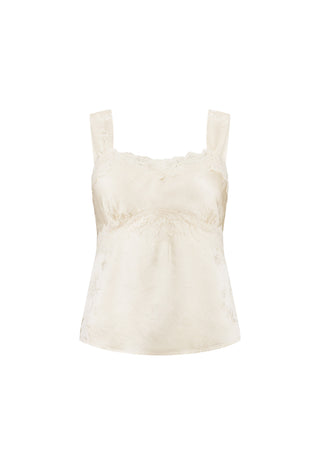 A woman wearing a white lace-trimmed camisole top and matching white skirt